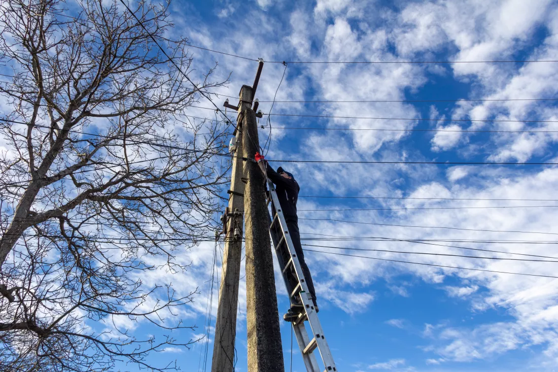 technician-working-ladder-maintain-fiber-optic-wires-attached-electric-poles